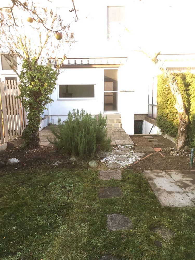 Garten hinter einem Wohnhaus mit Rasen und Trittplatten