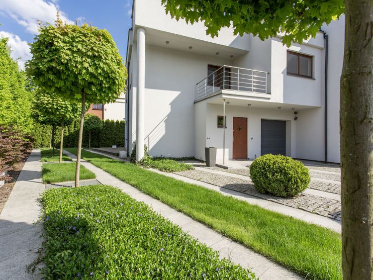 Gepflegter Vorgarten mit Kugelbäumen und Hecken vor einem modernen Wohnhaus